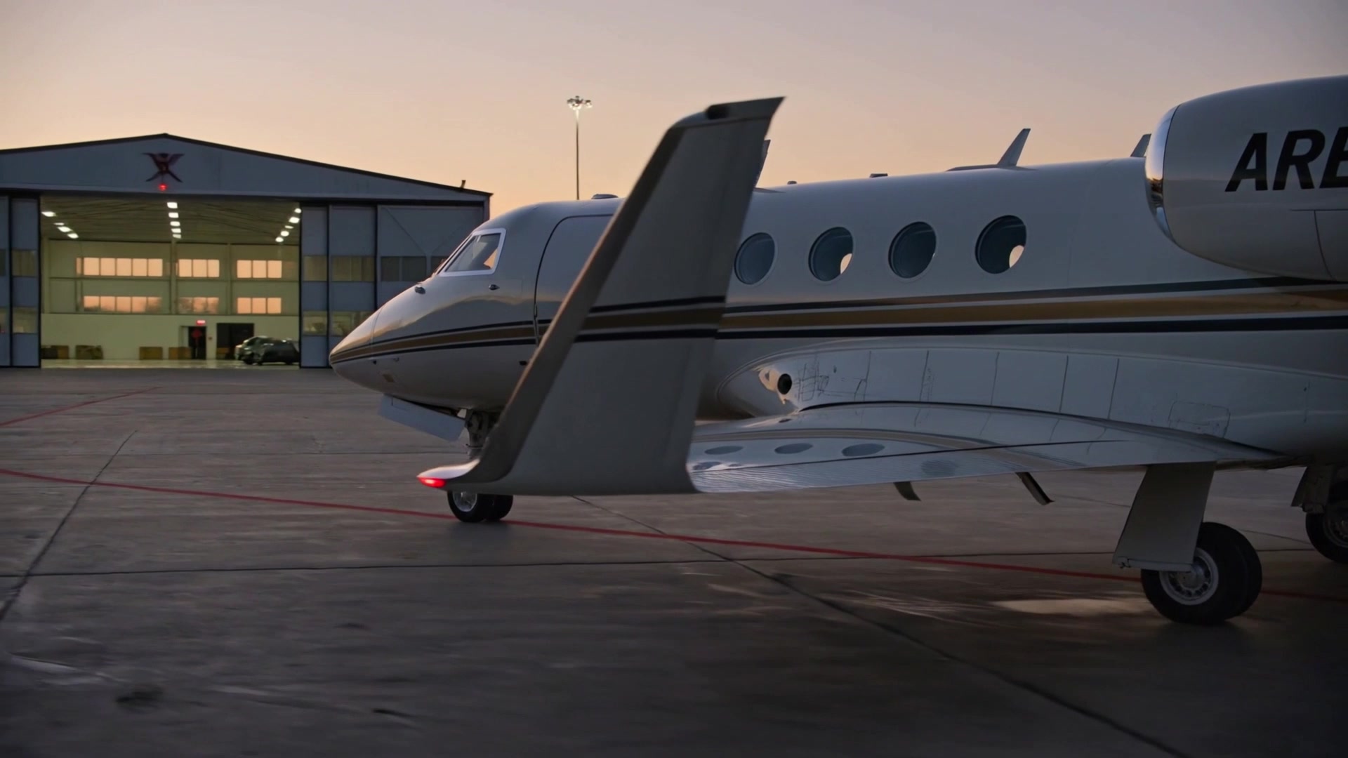 Silver business aircraft parked on a twilight apron